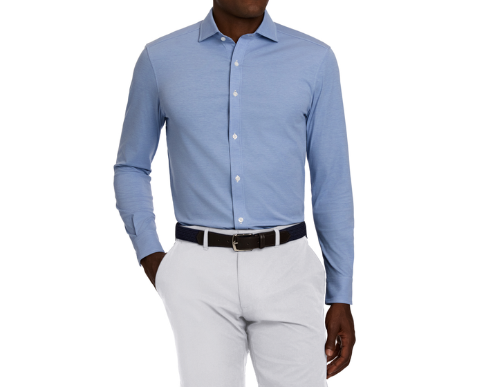 The Cullinane Shirt: Heathered Maidstone Blue, a light-blue button-down, is styled with a structured collar, tucked into pale trousers, showcasing its breathable, stretch fabric.