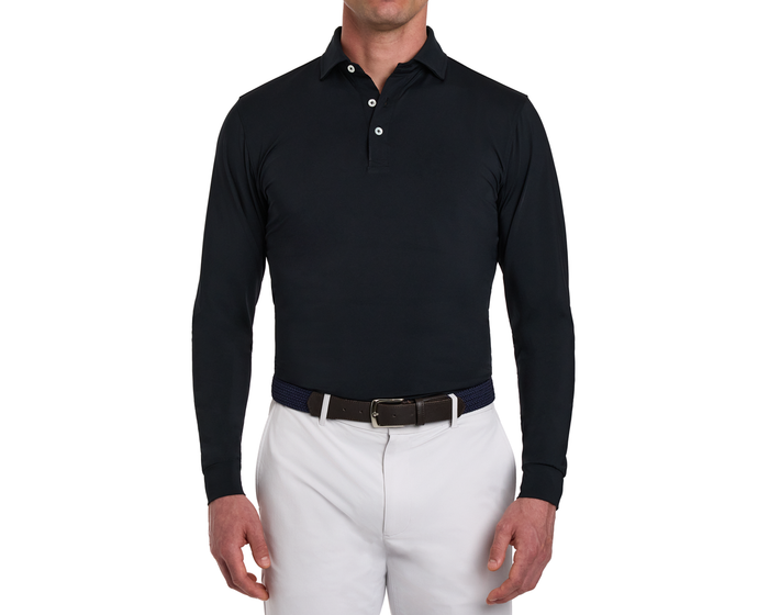 The Farrell Shirt: Black, long-sleeve polo with three-button placket, distinctive spread collar, worn with light trousers and a woven belt with leather accents.