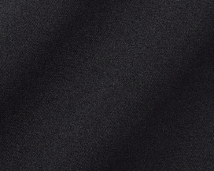 The Farrell Shirt: Black, close-up of textured performance jersey fabric with subtle folds, featuring long sleeves, spread collar, and contrast piping for versatile comfort and style.