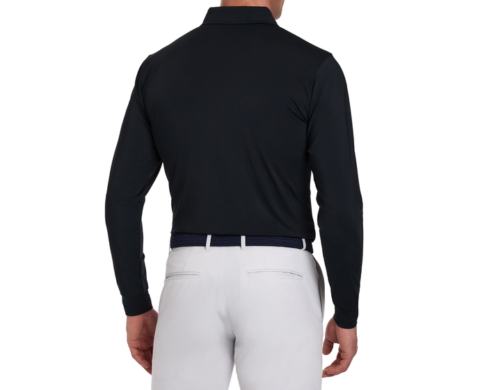 The Farrell Shirt: Black, long-sleeve polo with signature spread collar, tucked into light gray trousers, showcasing a sleek back view with a dark woven belt.