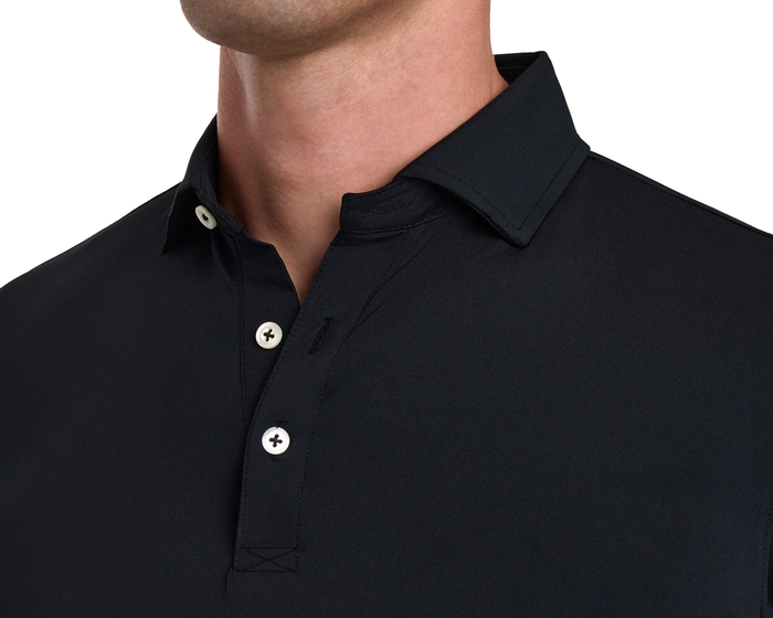 The Farrell Shirt: Black, long-sleeved polo with spread collar, unfastened buttons, and contrast piping. Offers moisture wicking and comfort with a soft hand feel.