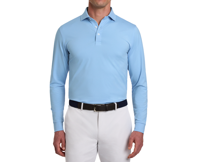 Man wearing The Farrell Shirt: Vista Blue, a light-blue long-sleeve polo with a woven belt, showcasing its comfort and performance features.