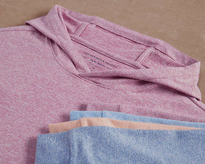 The Hamilton Hoodie: Heathered Cabernet & White features a subtle heathered stripe, lightweight performance blend, and visible Holderness & Bourne label on the folded pink-and-white shirt.