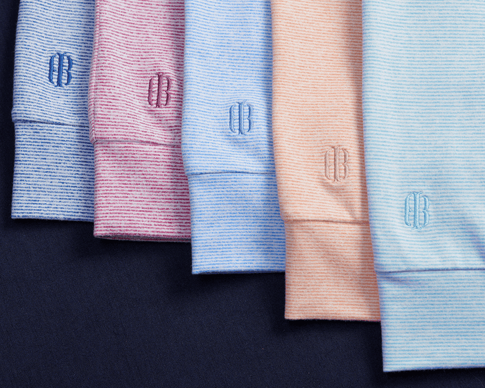 The Hamilton Hoodie: Heathered Harbor & White with fine stripes, folded neatly, showcasing the CB monogram on cuffs, highlighting comfort and versatility.