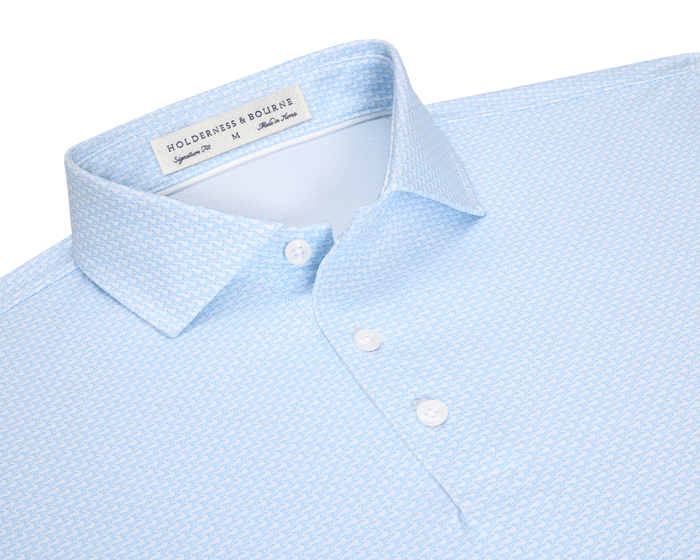 The Hanover Shirt: Vista Blue, a light-blue short-sleeve polo with a micro-pattern, features a structured collar, three-button placket, and signature fit.