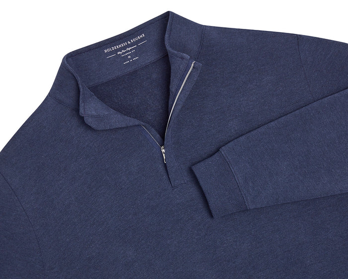 The Harper Quarter-Zip: Heathered Atlantic, a navy-blue pullover with a quarter-zip collar, ribbed cuffs, and hem, displaying Holderness & Bourne on the inside tag.