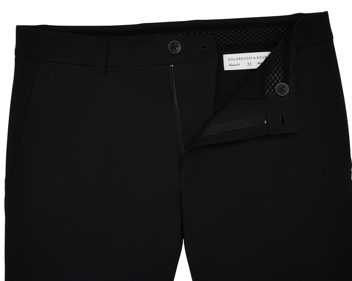 The Harwood Short: Black, displayed with a partly open zipper and undone button, revealing a Holderness & Bourne label and size 32 inside the waistband.