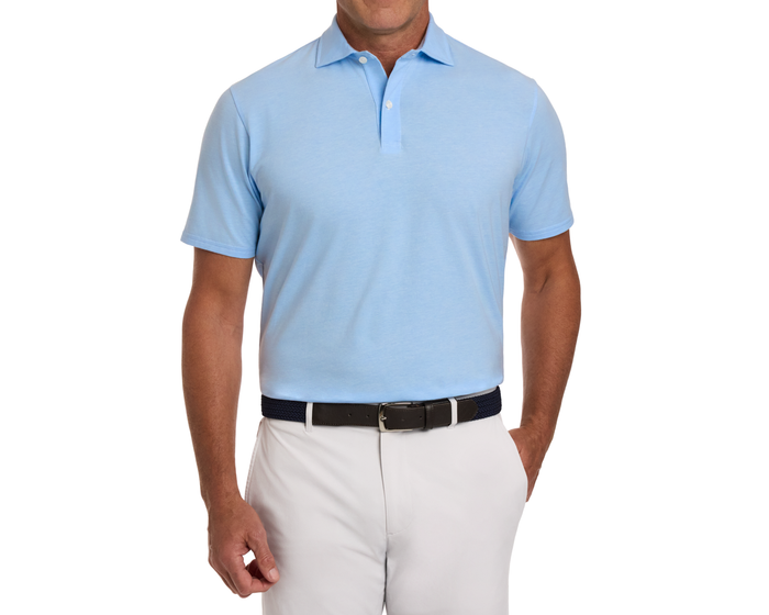 Man wearing The Hatcher Shirt: Vista Blue & White, a light-blue polo with a structured collar, tucked into pale trousers with a dark woven belt.
