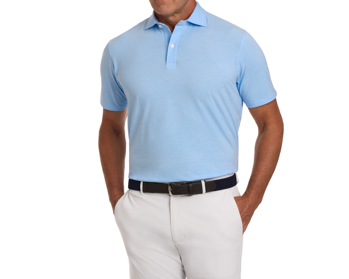 Man wearing The Hatcher Shirt: Vista Blue & White, a light-blue polo in soft Peruvian Pima cotton, tucked into off-white trousers with a dark braided belt.