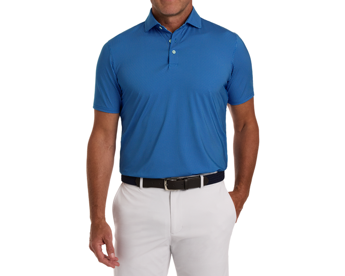 Man wearing The Hicks Shirt: Maidstone Blue, a blue patterned polo with short sleeves, tucked into light pants, showcasing a polished, breathable design suitable for golf.