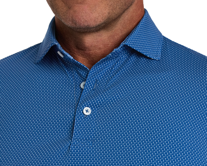 The Hicks Shirt: Maidstone Blue features a geometric pattern, pointed collar, and two white buttons, crafted for performance with moisture wicking and sun protection.