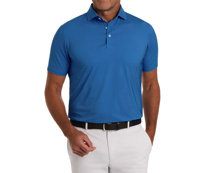 The Hicks Shirt: Maidstone Blue, featuring a dot-patterned texture, short sleeves, and a structured collar, is styled with light gray pants and a dark belt.