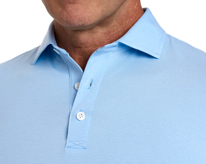 The Holland Shirt: Heathered Vista Blue, featuring a textured light-blue fabric, spread collar, and two white buttons, showcases a sophisticated, layered design.