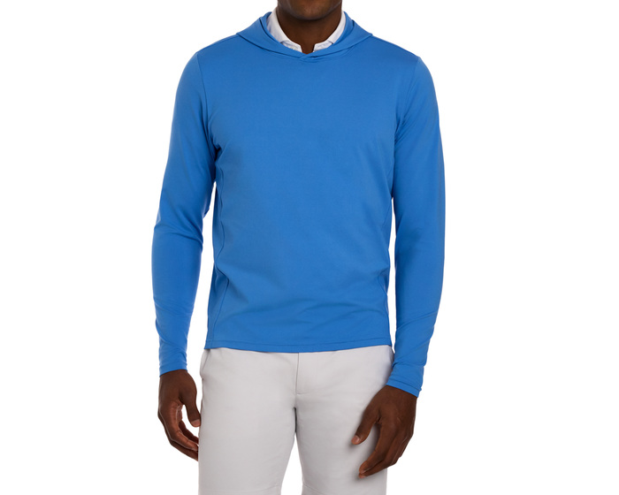 Man wearing The Jackson Hoodie: Horizon Blue, a lightweight, long-sleeve athletic top, over a white collared layer, paired with light gray pants.