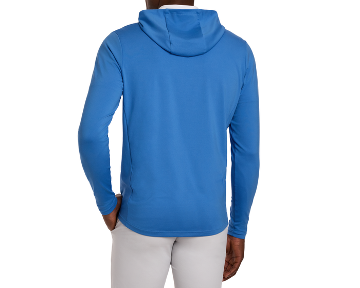 Person wearing The Jackson Hoodie: Horizon Blue, featuring a streamlined design without drawstrings, paired with light grey pants, highlighting the hoodie’s lightweight, performance fabric.
