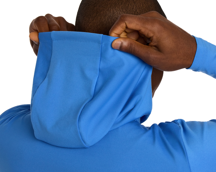 Person adjusting hood of The Jackson Hoodie: Horizon Blue, showcasing its lightweight, streamlined design without drawstrings, ideal for enhancing movement during golf.