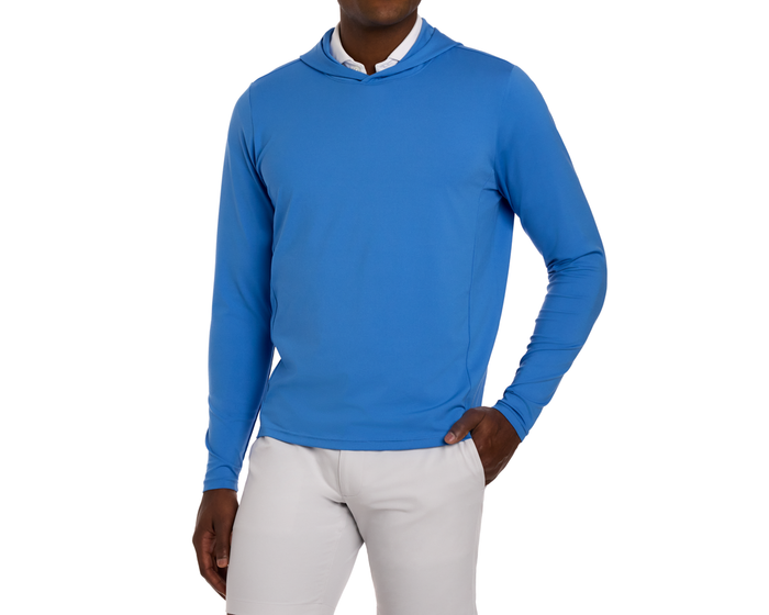 The Jackson Hoodie: Horizon Blue, a sleek, lightweight pullover, worn over a white shirt, designed for unrestricted golf swings, shown on a male model.