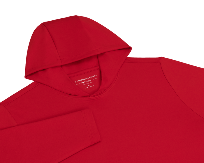The Jackson Hoodie: Liberty, a streamlined red hoodie with a hood, left sleeve visible, and Holderness & Bourne label inside the collar.