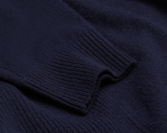 The Logan Hoodie Sweater: Heathered Navy features a close-up of the ribbed knit cuff, highlighting its luxurious Merino wool and cashmere blend.