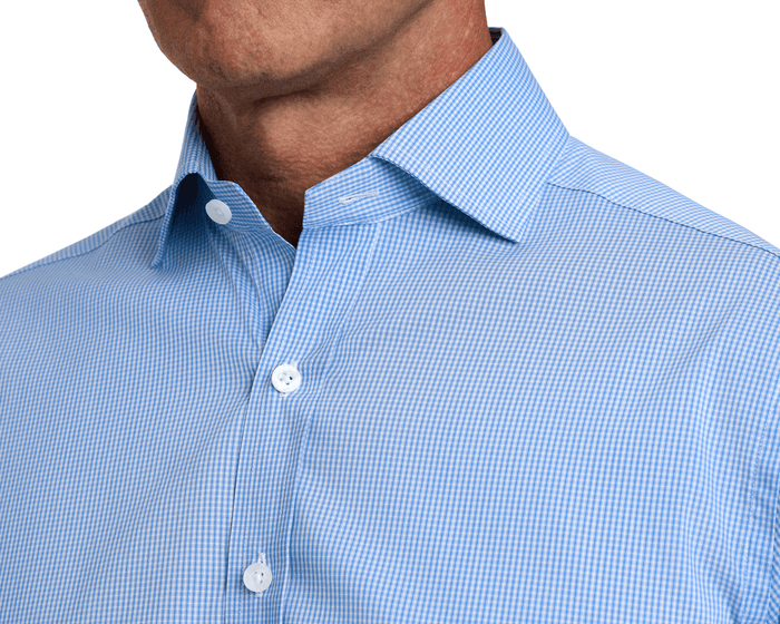The McAllister Shirt: Horizon Blue features a light-blue gingham pattern, spread collar, white buttons, offering breathability, stretch, and wrinkle resistance for all-day comfort.