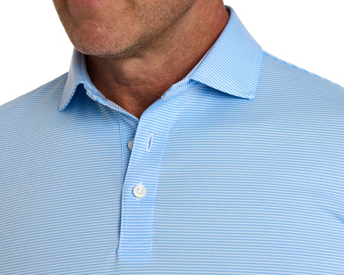 The Perkins Shirt: Vista Blue & White, featuring a light blue polo with fine white stripes, folded collar, and button placket, worn by a man.
