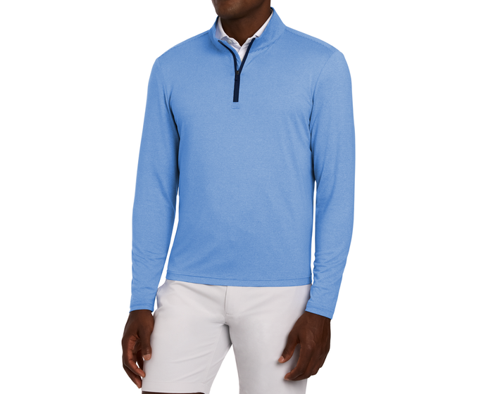 Male model wearing The Royce Quarter-Zip in Heathered Horizon Blue over a white shirt, paired with light trousers. The sporty-casual pullover features a darker zipper placket.