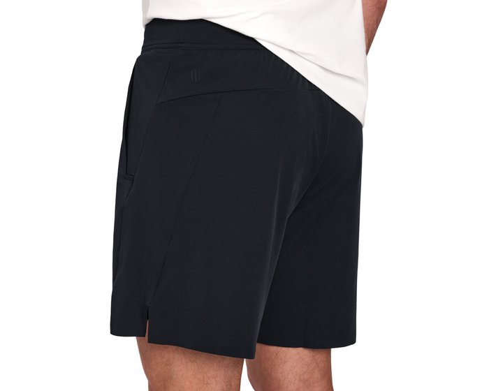 The Saunders Short: Black, featuring mid-thigh length, angled seams, side and zip pockets, and a slit hem, ideal for workouts with breathable, stretchy fabric.