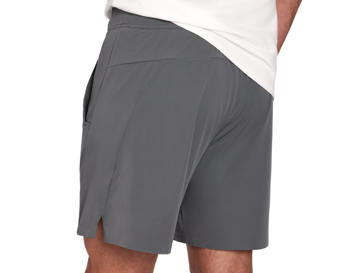 The Saunders Short: Iron Gray, featuring a small side slit and pocket detail, worn with a white shirt tucked slightly in.