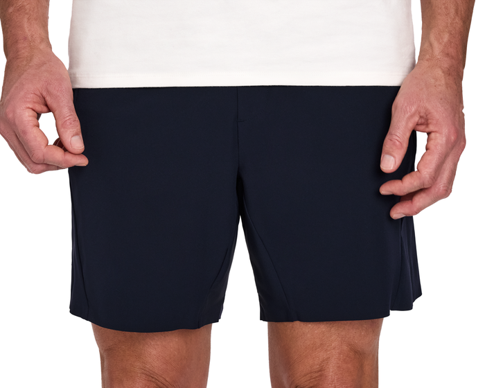 The Saunders Short: Navy, featuring quick-drying fabric, four-way stretch, and multiple pockets, shown worn by a model with a tucked white shirt.
