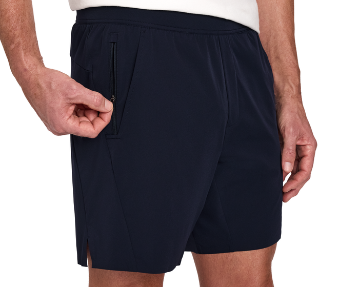 The Saunders Short: Navy, featuring a hand unzipping the right side pocket, highlighting the elastic waistband and side slit for comfort and utility.
