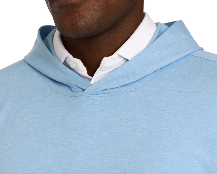 Person wearing The Stowe Hoodie: Heathered Vista Blue over a white collared shirt, highlighting its lightweight, ultra-soft fabric and athletic drop-tail hem.