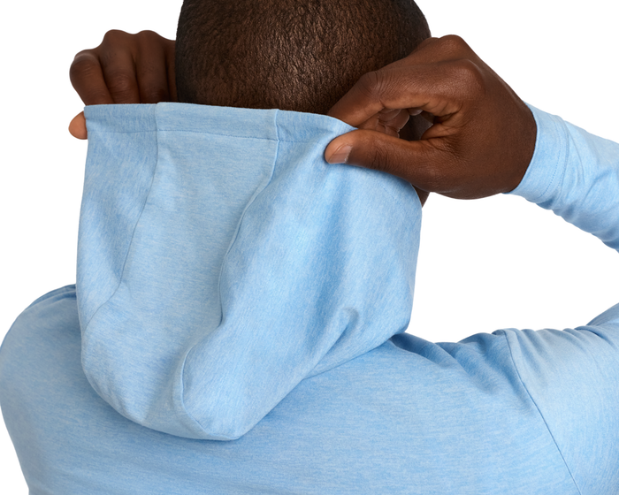 Person wearing The Stowe Hoodie: Heathered Vista Blue, showcasing the back with detailed stitching and texture as they pull the hood up over their head.