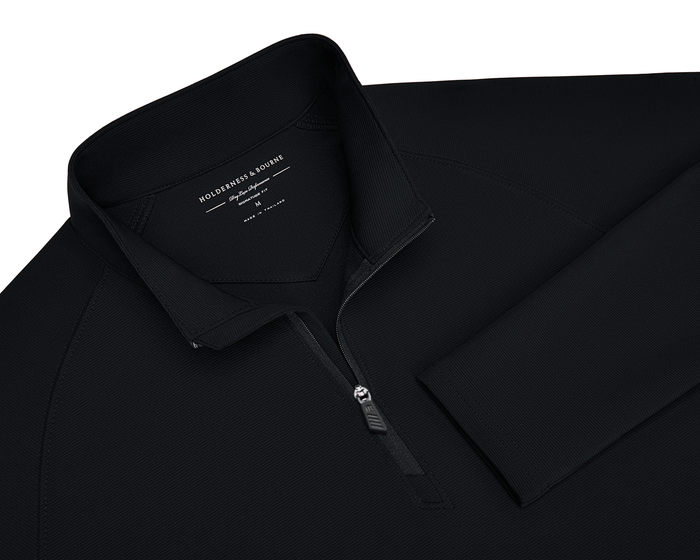 The Stuart Quarter-Zip: Black pullover with a ribbed texture, standing collar, and logo zipper. Features a soft interior and Holderness & Bourne label.