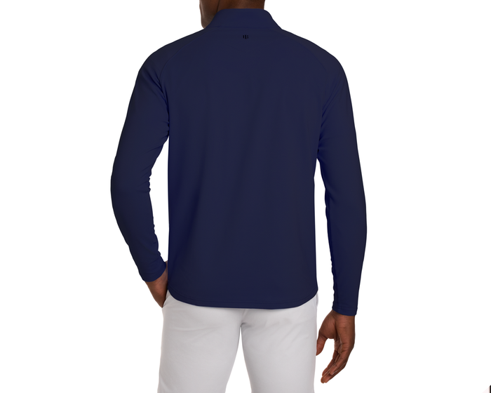 A male model wears The Stuart Quarter-Zip: Navy, showcasing its textured rib fabric and stand-up collar, paired with white pants.