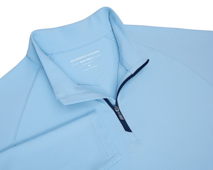 The Stuart Quarter-Zip: Vista Blue, a lightweight performance pullover with a ribbed collar and navy zipper, showcasing a luxurious blend and subtle textured fabric.