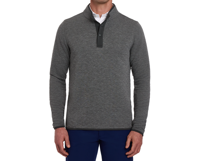 Model wearing The Sullivan Quarter-Snap: Heathered Charcoal pullover with snap-button placket, layered over a white collared shirt, paired with dark navy trousers.