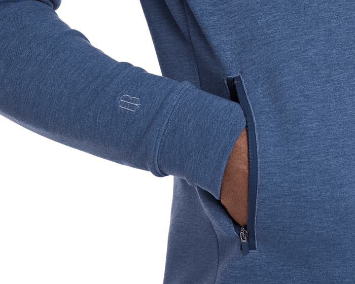 The Tilley Quarter-Zip Hoodie: Heathered Andover features a zippered side pocket and embroidered cuff logo, showcasing its sleek, versatile design for cool-weather activities.