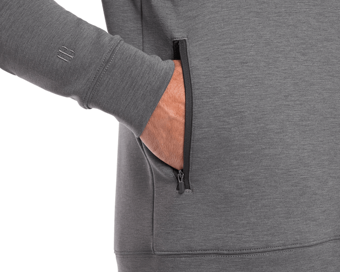 Person wearing The Tilley Quarter-Zip Hoodie: Heathered Charcoal, showcasing a sleek silhouette with a small zippered side pocket, ideal for versatile, cool-weather wear.