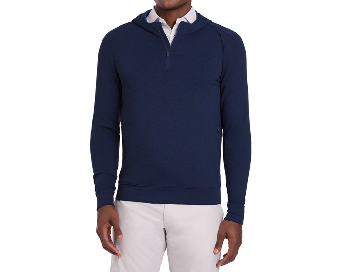 Man wearing The Tilley Quarter-Zip Hoodie: Heathered Navy, showcasing its sleek silhouette over a white collared shirt, paired with light trousers.