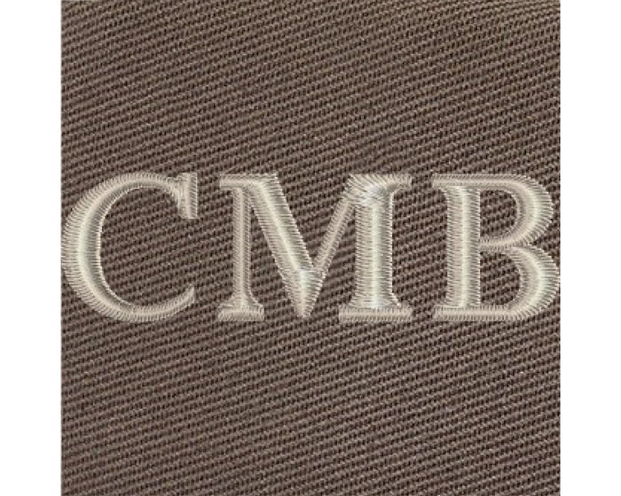 The Travis Tote Bag features cream-white CMB embroidery on brown woven fabric, showcasing personalized initials on its durable cotton twill design.