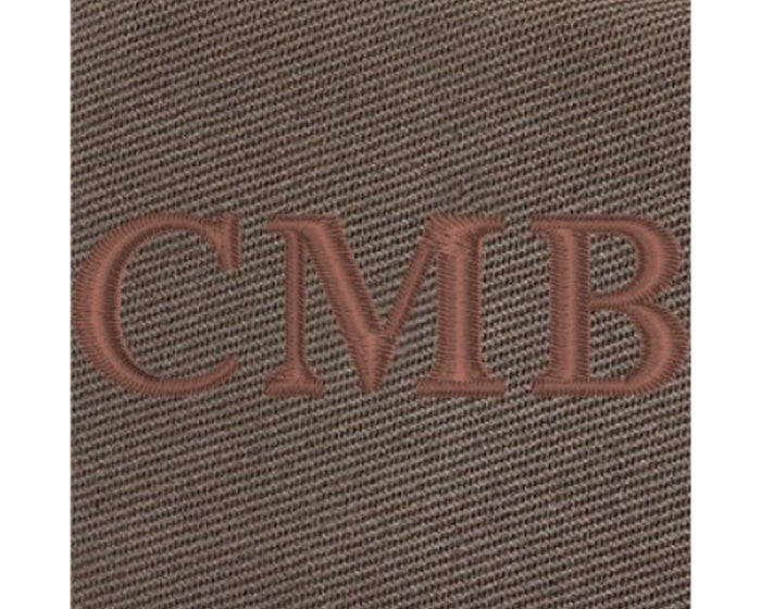 The Travis Tote Bag Cotton Twill: Close-up of brown textured fabric with CMB embroidered, showcasing personalized whiskey embroidery on durable, versatile tote.