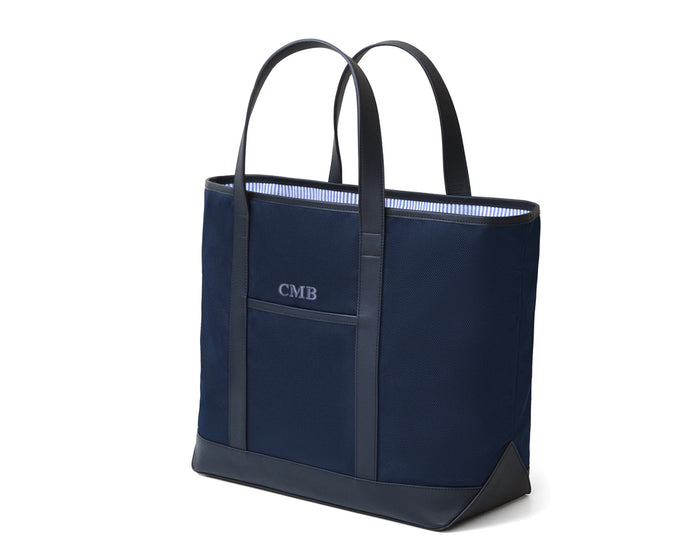 The Treadwell Tote: Navy Ballistic - Slate Blue Embroidery, featuring leather trim, a front slip pocket, and striped interior, subtly monogrammed CMB.