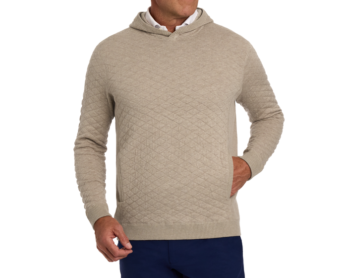 The Wallace Hoodie Sweater: Heathered Light Dune, features a diamond-quilted knit design, subtle kangaroo pocket, over a white shirt, paired with navy trousers.
