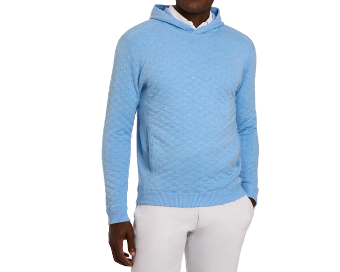 Person wears The Wallace Hoodie Sweater: Heathered Vista Blue, showcasing quilt texture and ribbed side panels over a white collared shirt.