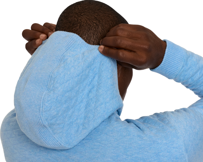Person pulls hood over head, showcasing The Wallace Hoodie Sweater in Heathered Vista Blue, made of soft Egyptian cotton with ribbed side panels.
