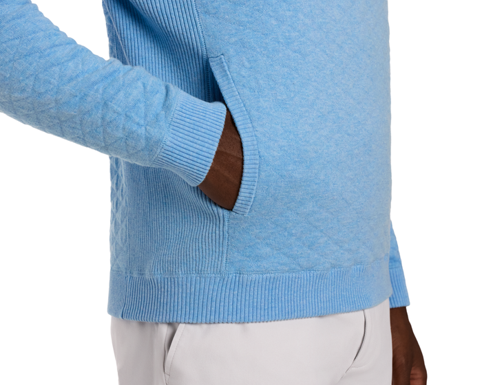 Person wearing The Wallace Hoodie Sweater: Heathered Vista Blue, showcasing ribbed cuffs, hem, side-entry pouch pocket, and streamlined fit with light-colored pants.