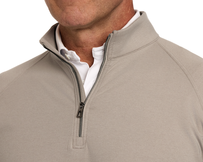 Man wearing The Westland Quarter-Zip: Heathered Dune, a light-beige pullover with short zipper and white shirt collar visible underneath, showcasing versatile, moisture-wicking fabric.