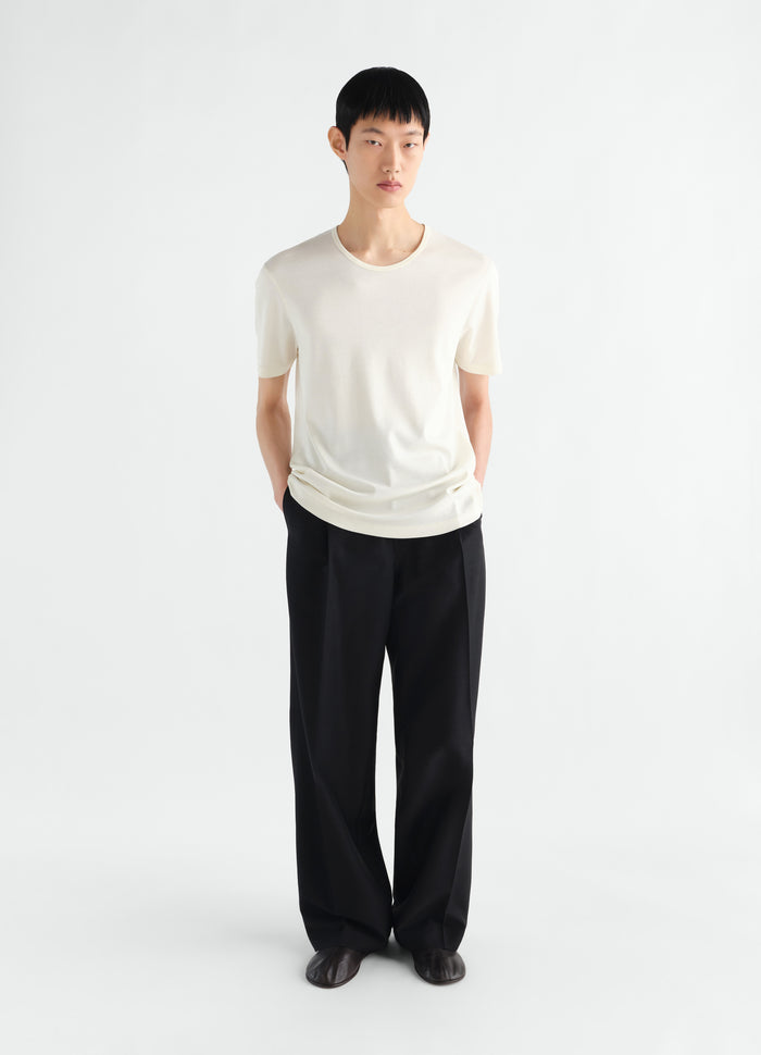 Scoop-neck ribbed jersey T-shirt in off-white worn by model with black wide-leg trousers LEMAIRE front view
