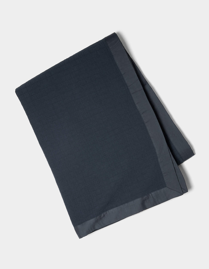 The Cozy Earth Waterfront Grid Matelasse Blanket, shown neatly folded in dark blue with a smooth satin border, is displayed on a plain light background.|Color:Eclipse