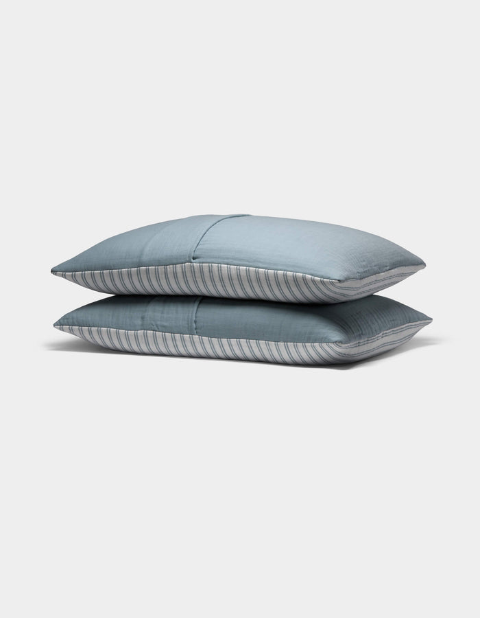 Two Waterfront Shams by Cozy Earth, featuring subtle blue stripes, are stacked neatly atop each other against a plain white background.|Color:River Stripe